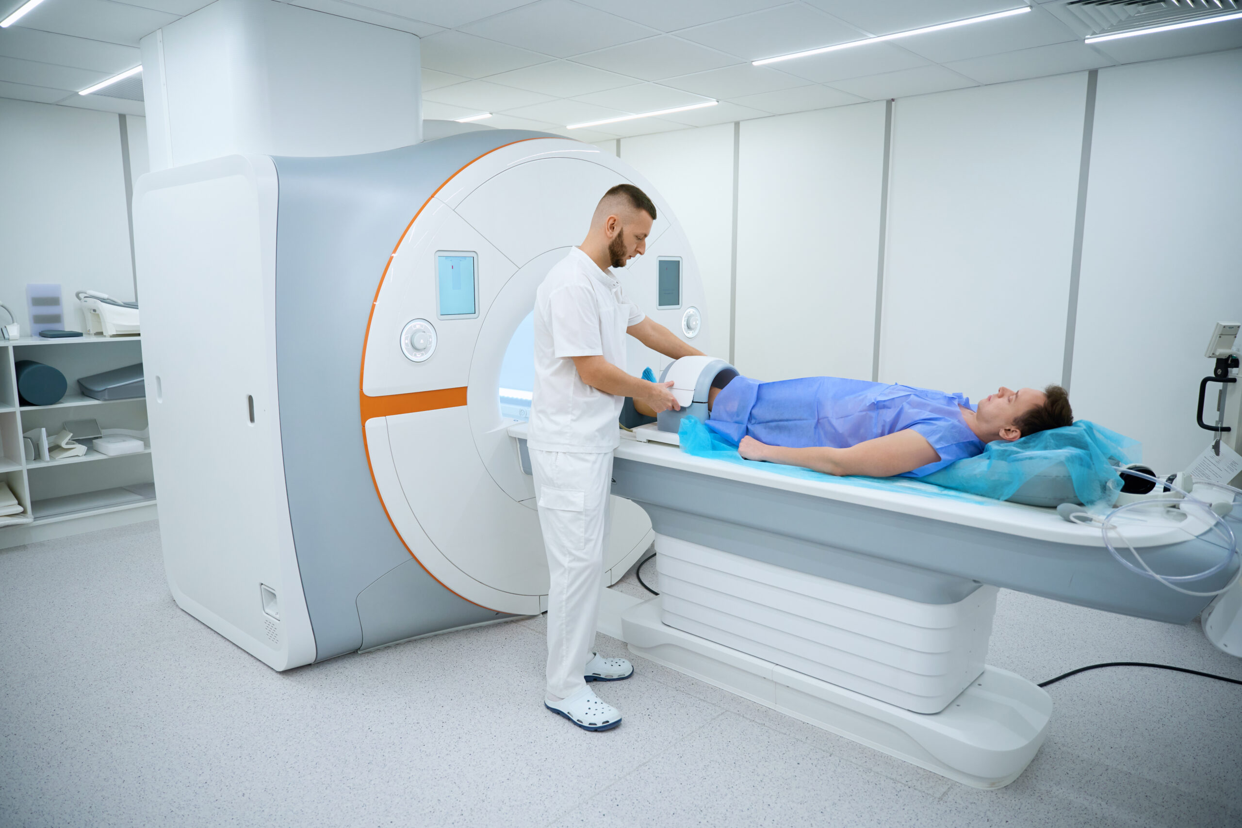 Medical professional preparing man for MRI of lower limb joint