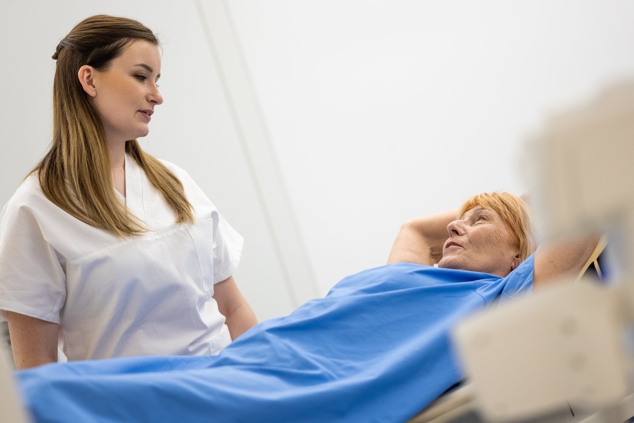 Doctor explaining MRI scan procedure to patient laying on MRI bed